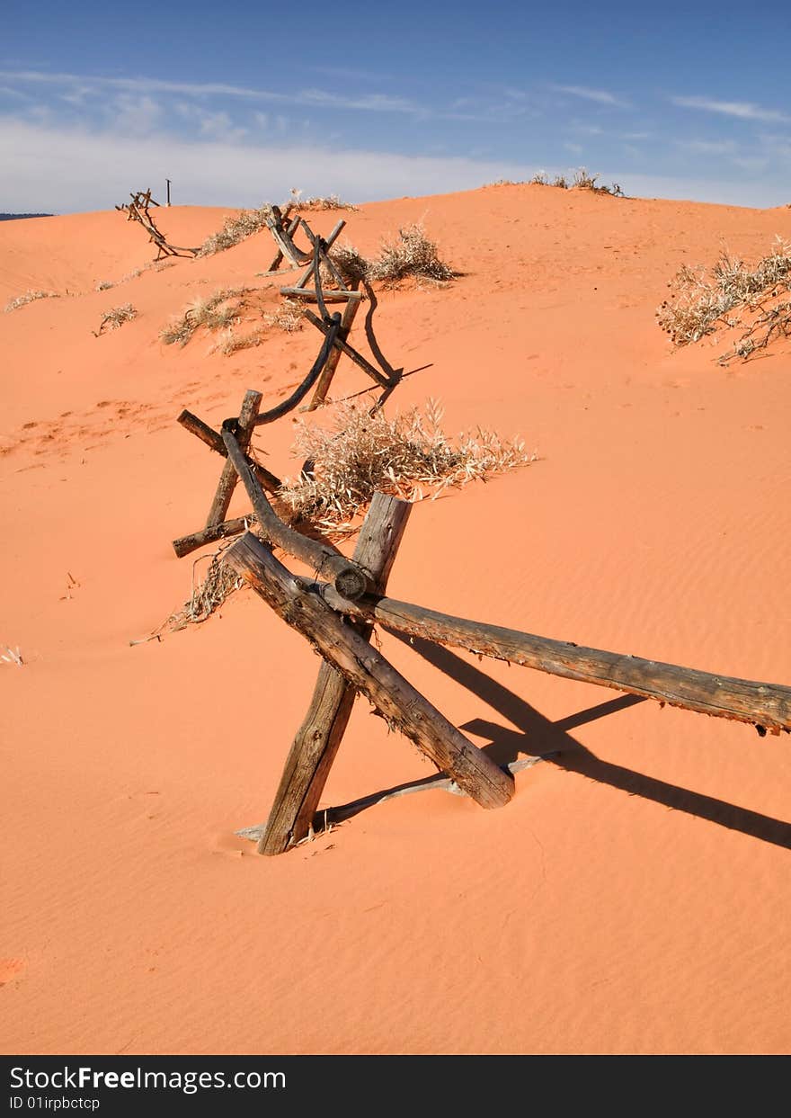 A log pole fence is slowly being engulfed by drifting sand. A log pole fence is slowly being engulfed by drifting sand