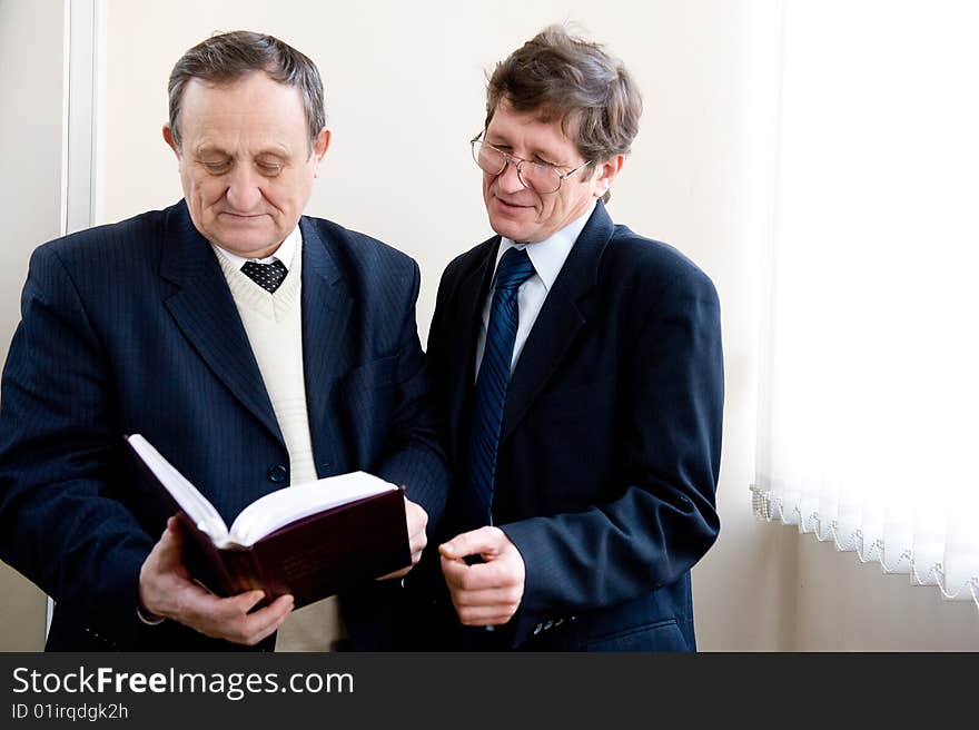 Portrait of a two senior businessmen reading the book