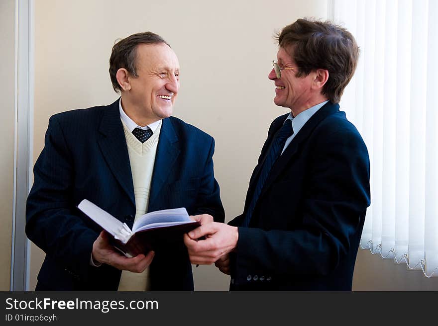 Portrait of a two senior businessmen reading the book