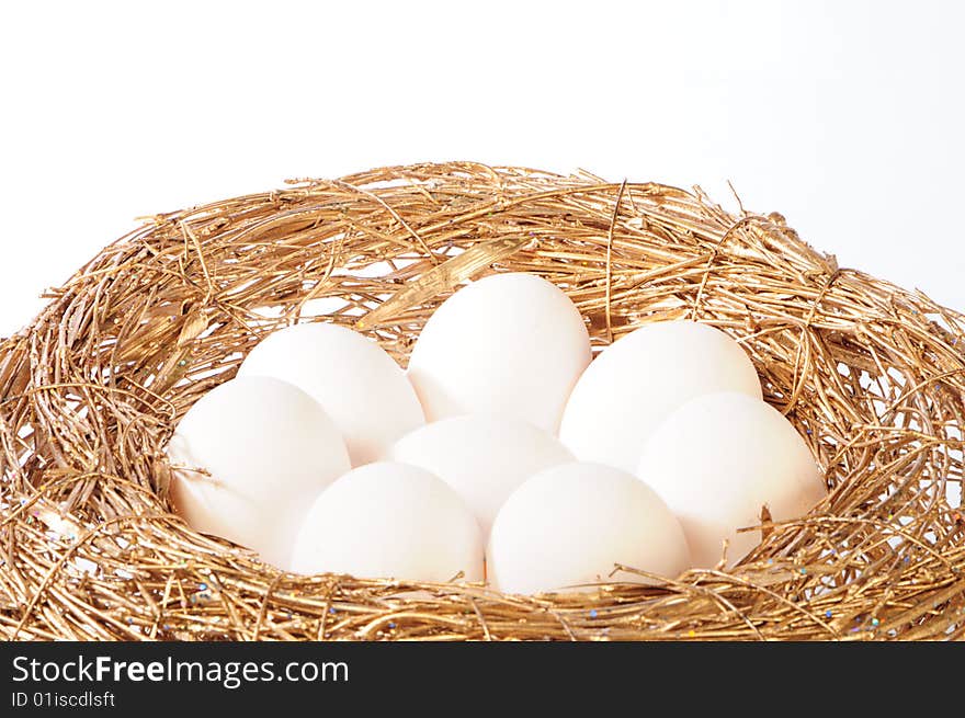 White eggs in golden nest on white