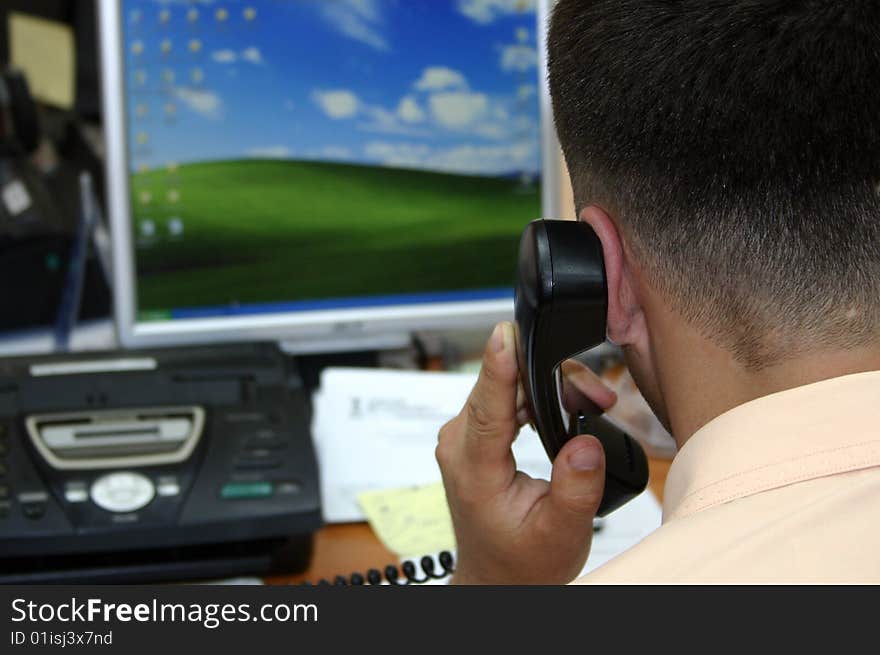 A regular office scene. Businessman speaking at the phone.