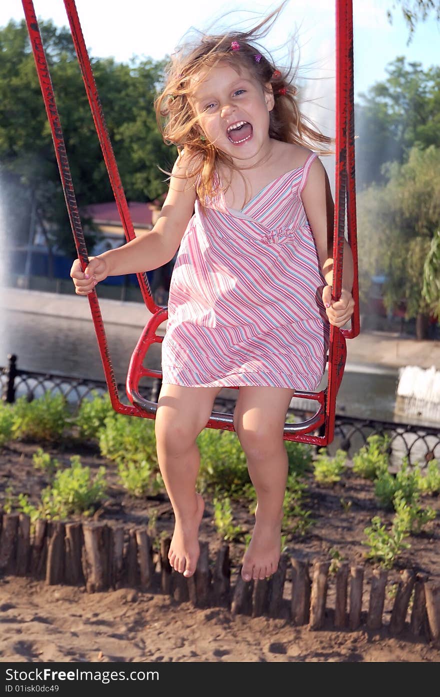 Little girl swinging in the park and shouting of happiness. Little girl swinging in the park and shouting of happiness