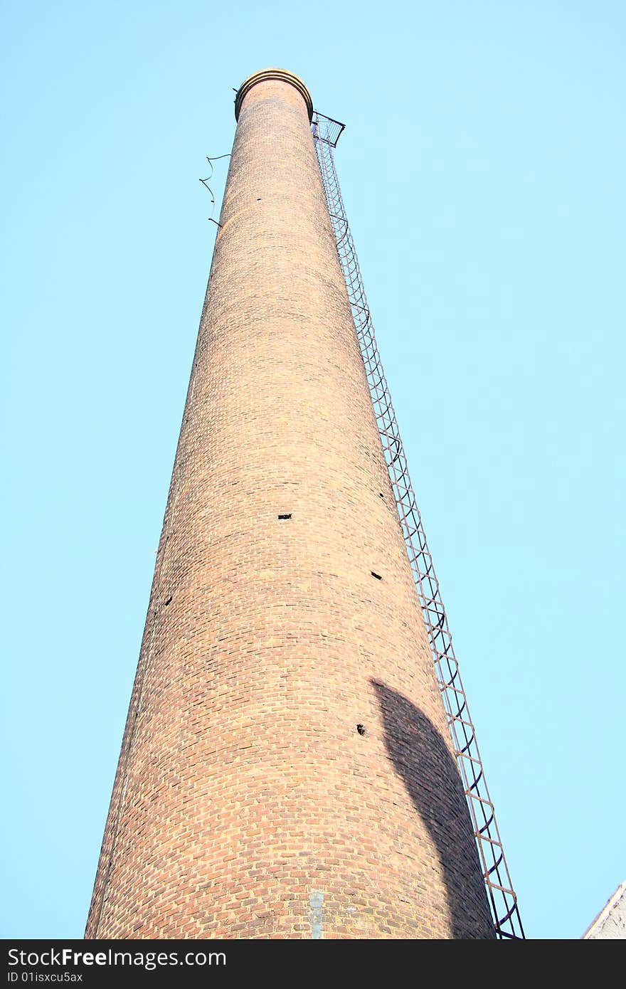 Industrial smokestack under blue sky.