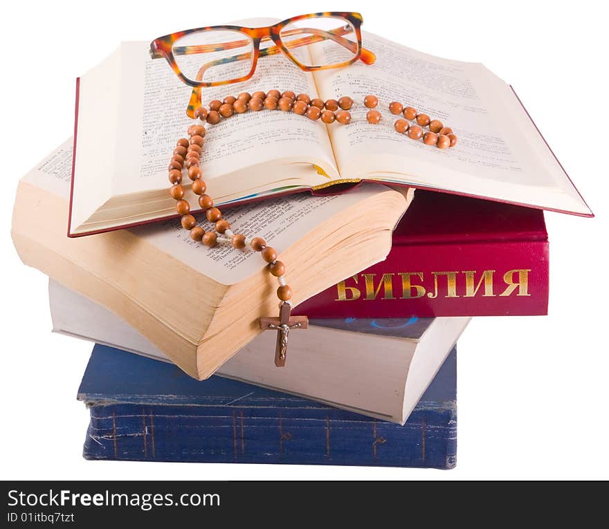 Open Holy Bible lying on stack of old books with glasses, cross and beads. Open Holy Bible lying on stack of old books with glasses, cross and beads