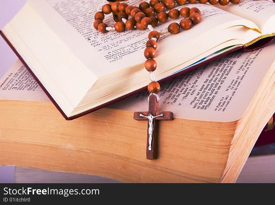 Open Holy Bible lying on stack of old books with glasses, cross and beads. Open Holy Bible lying on stack of old books with glasses, cross and beads