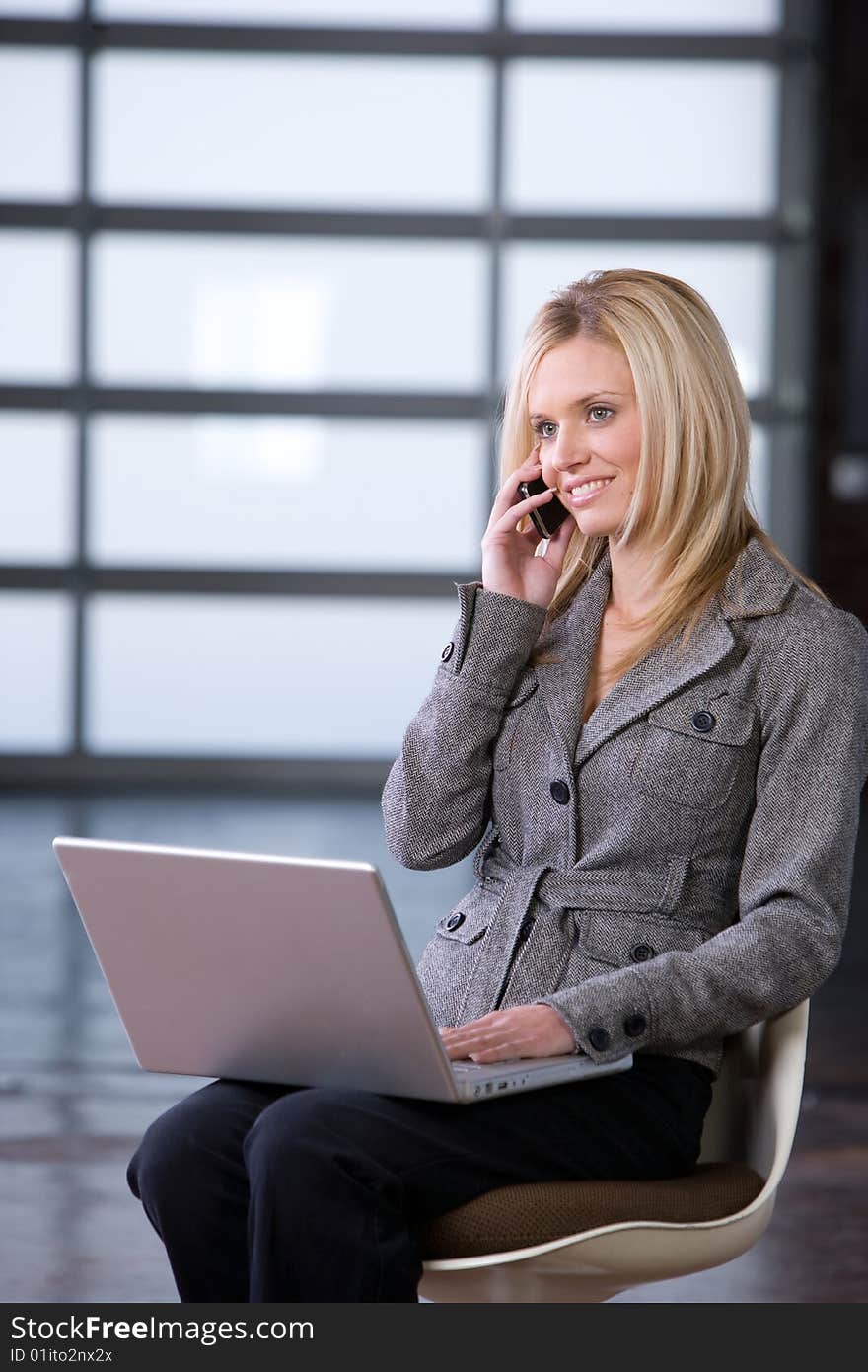 Business Woman on a cell phone and laptop in modern office