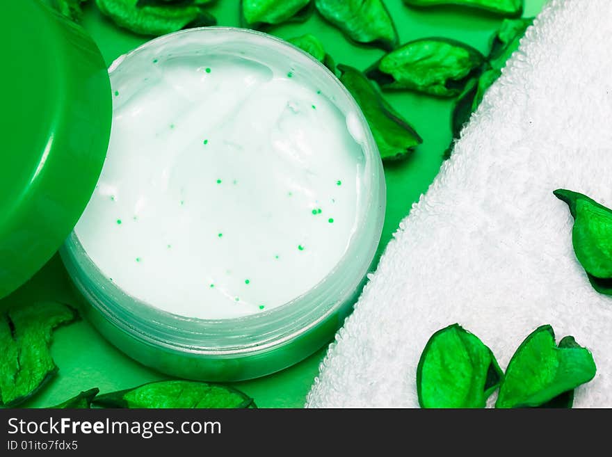 Spa essentials, cream and towel with green petals