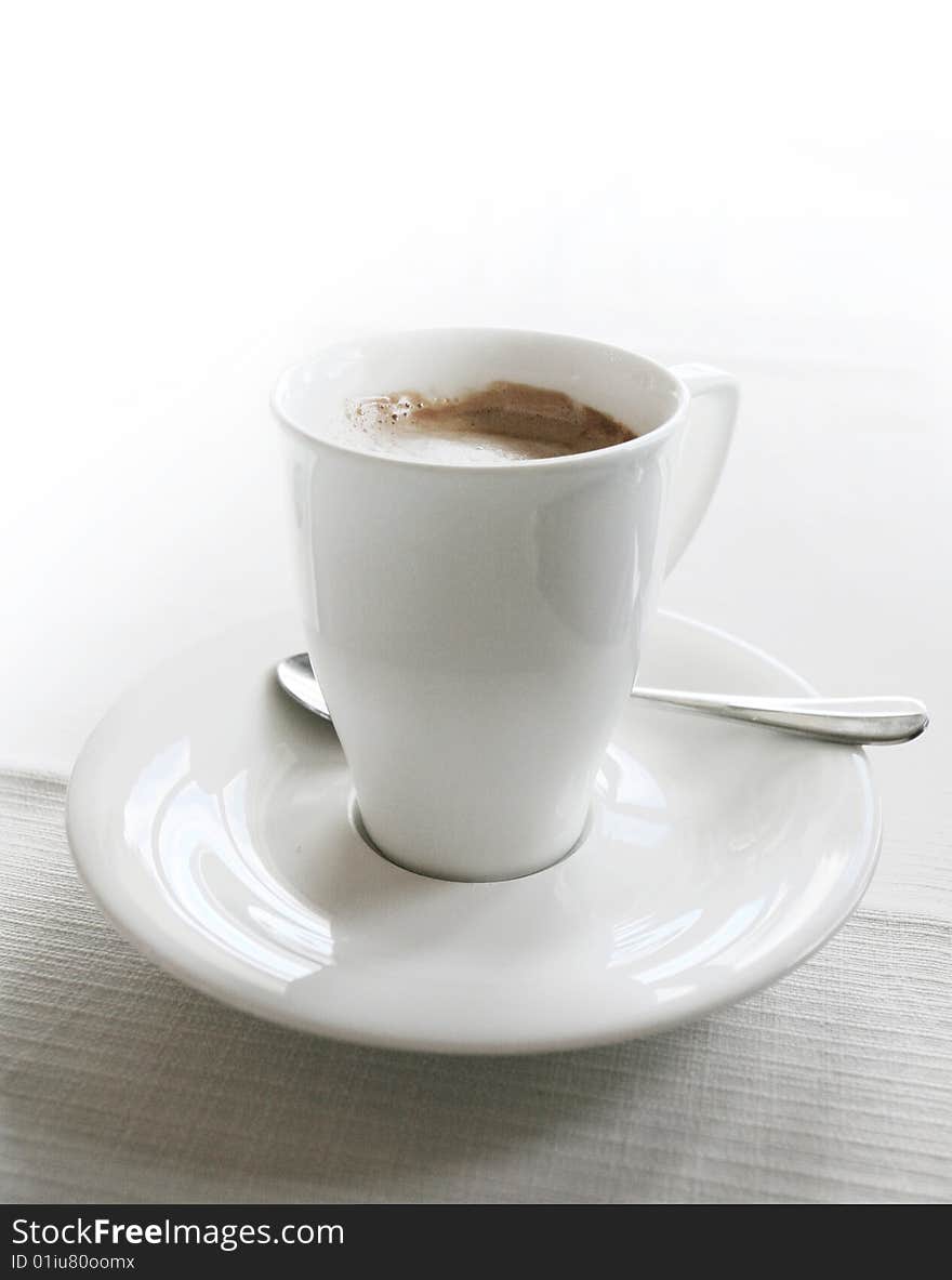 Coffee in white cup over white table. Coffee in white cup over white table