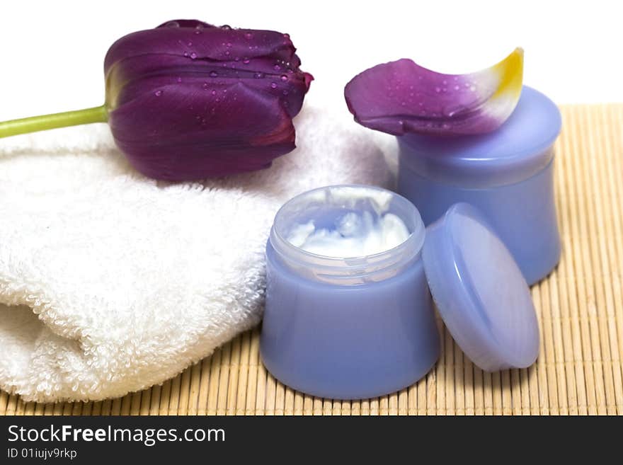 Spa essentials (cream, white towel and violet flower)