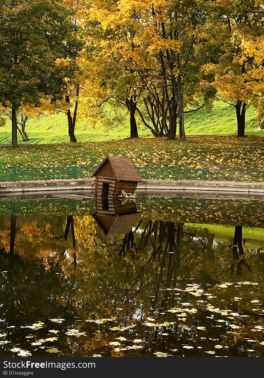 A park lake with a duck house on water. A park lake with a duck house on water