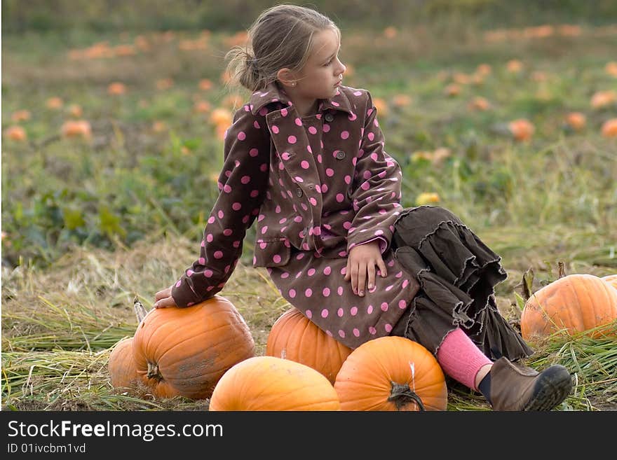 Pretty child sitting on a pumpkin