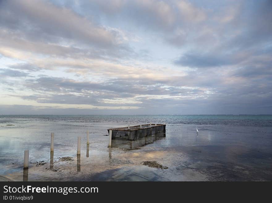 A lone egret and fish-holding pen at sunset along the shore of Ambergris Caye in Belize. A lone egret and fish-holding pen at sunset along the shore of Ambergris Caye in Belize.