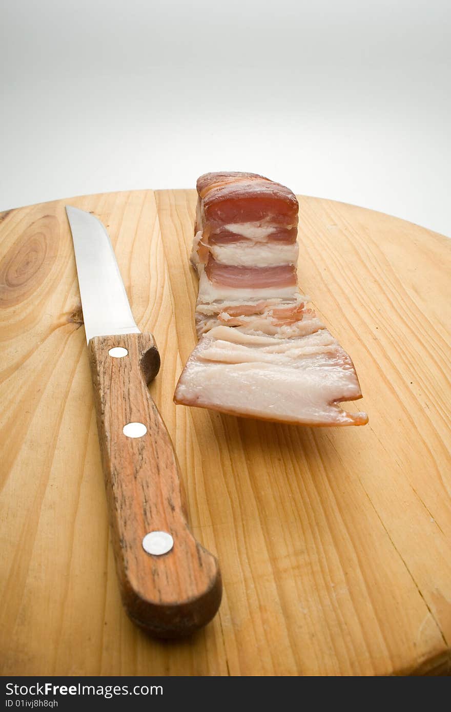 Bit ofbacon and knife on kitchen chopping board. Bit ofbacon and knife on kitchen chopping board