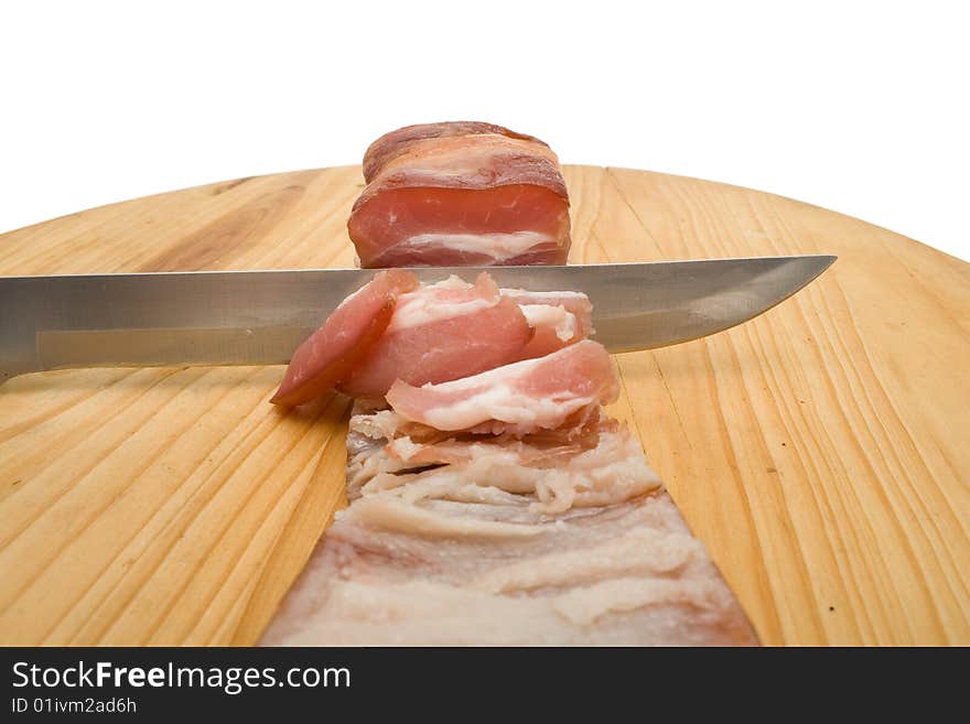 Knife cutting bacon on chopping board