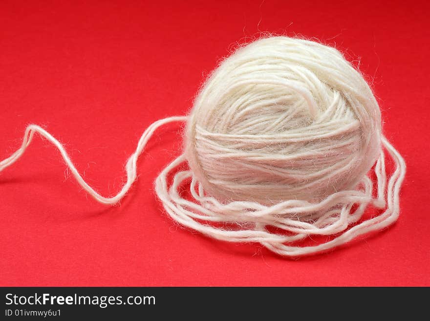 Ball of white wool on a red background