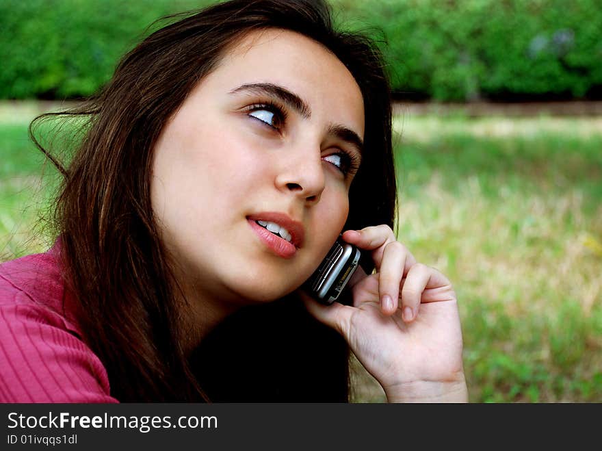 Pretty teenage girl on cellphone in the park