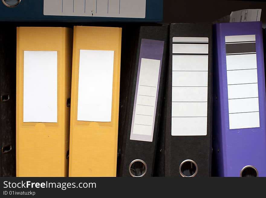 Colored folders are on a shelf in a row. Colored folders are on a shelf in a row