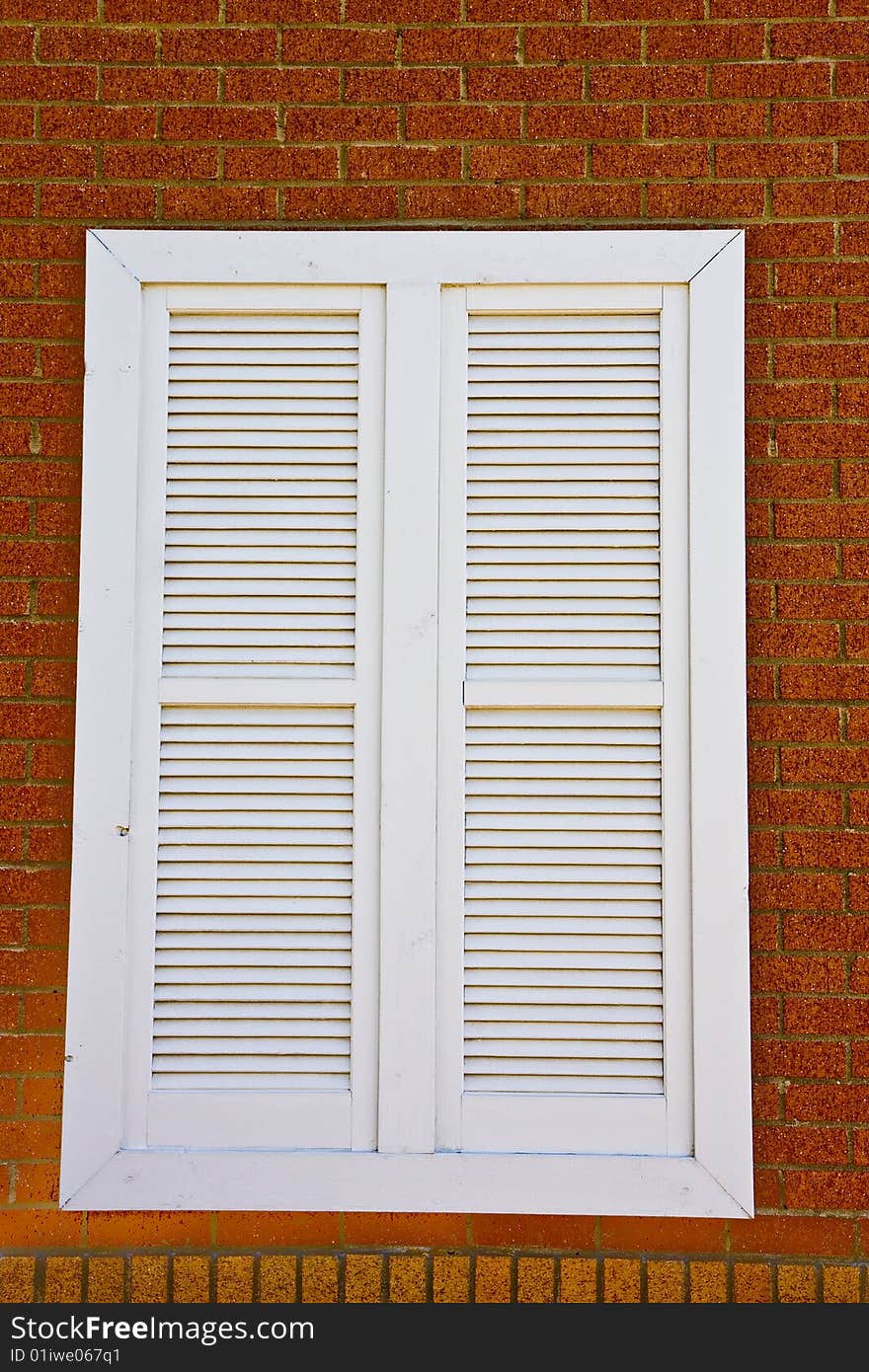 WhiteLouvered window on a red brick wall. WhiteLouvered window on a red brick wall