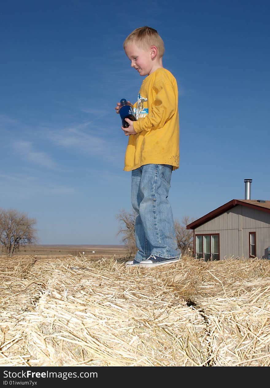 A color image of a young boy standing on a hay pile. A color image of a young boy standing on a hay pile.
