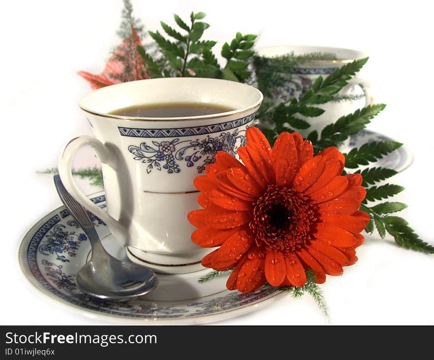 Two coffe cups with one red flower with morning dew or raindrops. Two coffe cups with one red flower with morning dew or raindrops