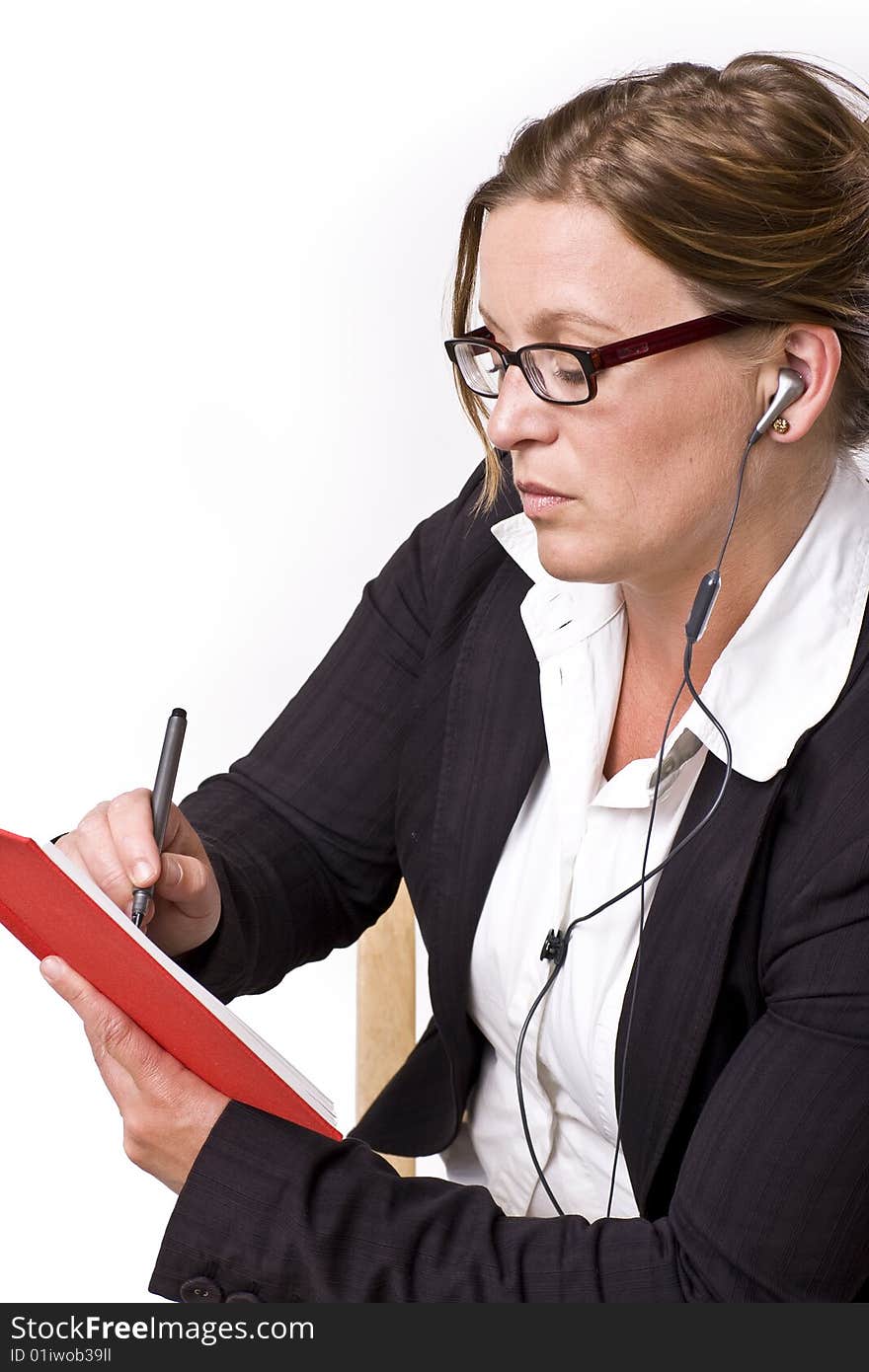 Businesswoman taking notes in a red notebook and handsfree