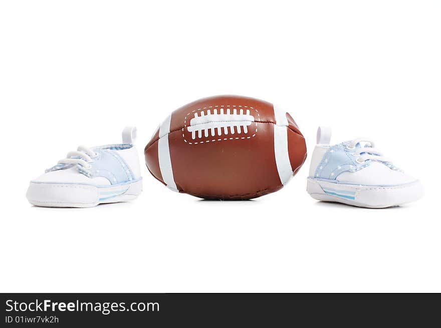 Football with baby shoes against a white background.