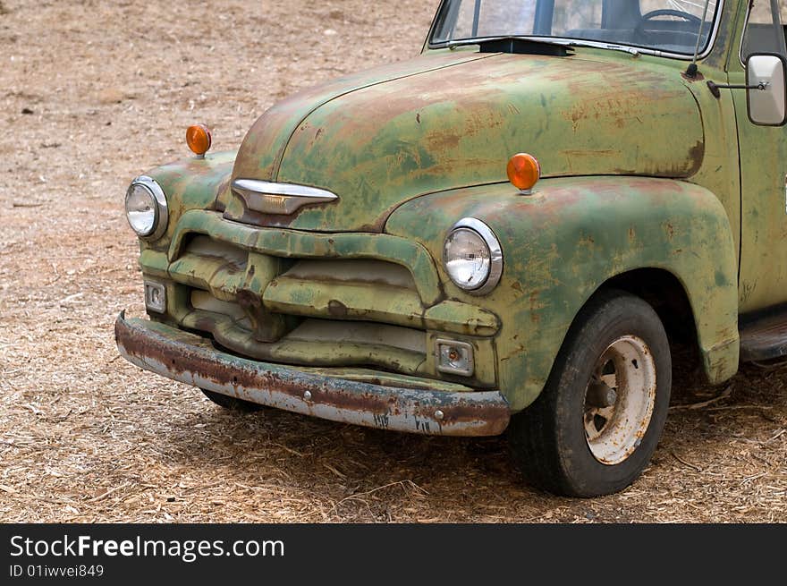 A close-up on an old rusty Chevrolet covered with chipped green paint. Cropped. The file contains an embedded clipping path. A close-up on an old rusty Chevrolet covered with chipped green paint. Cropped. The file contains an embedded clipping path.