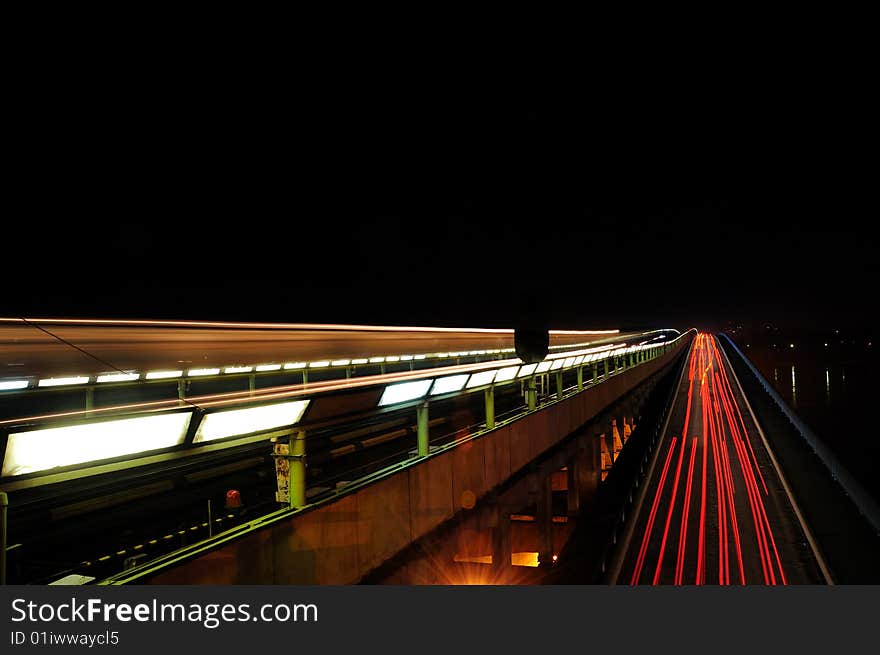 Movement of cars and a train on a city bridge at night. Movement of cars and a train on a city bridge at night