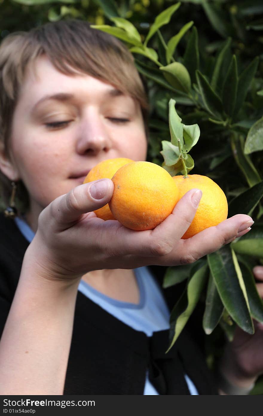 A girl smells ripe orange in orchard