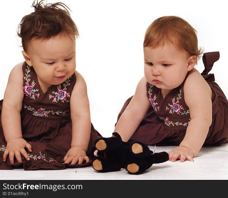 Two adorable little babies wearing brown dresses isolated against white background. Two adorable little babies wearing brown dresses isolated against white background