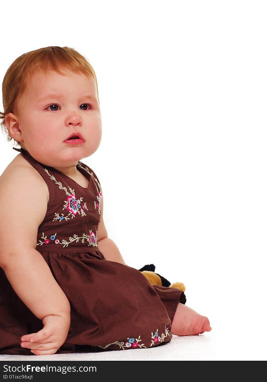 Adorable little baby wearing brown dress holding toy isolated against white background