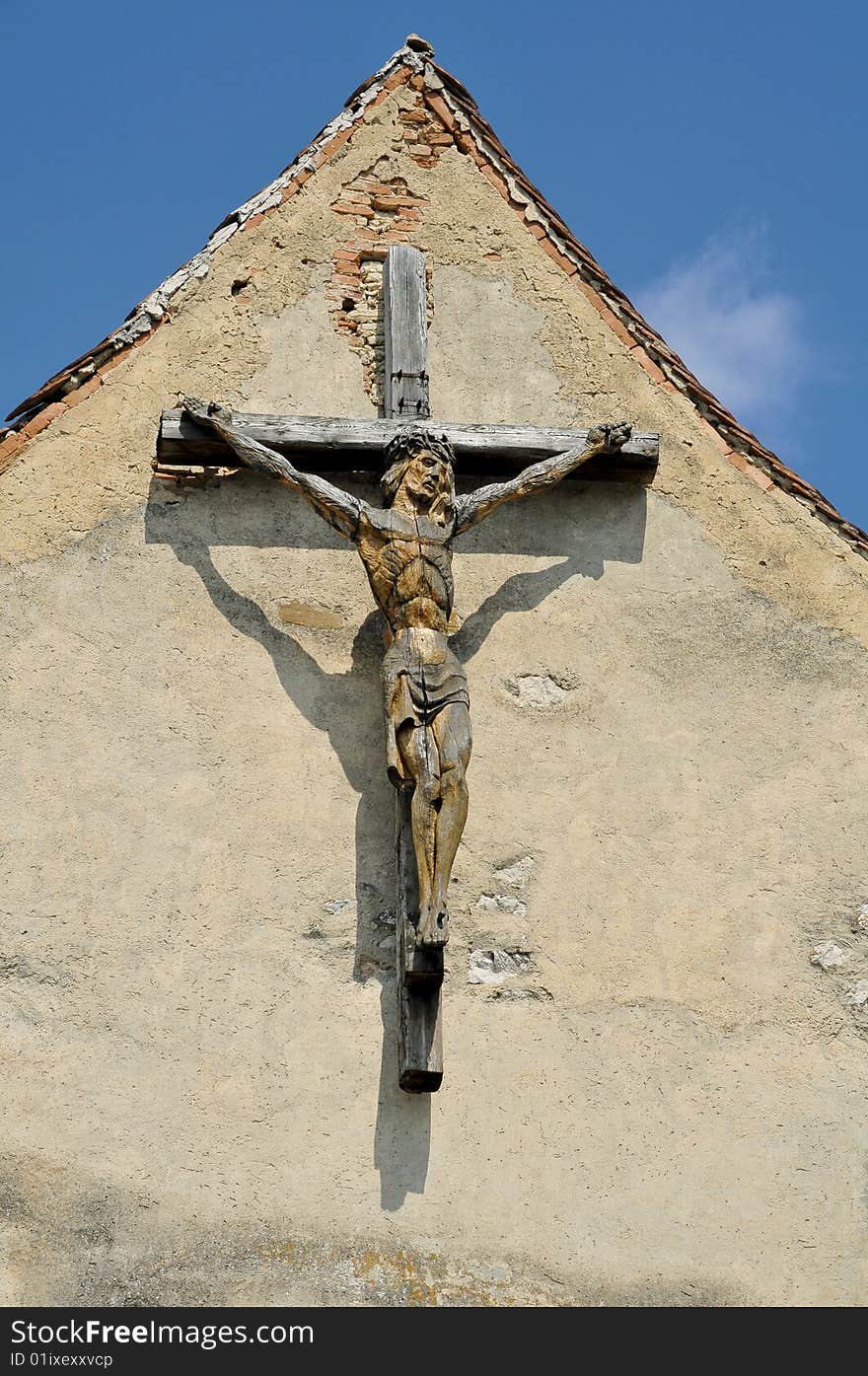 Wooden cross with sculpted jesus on a building