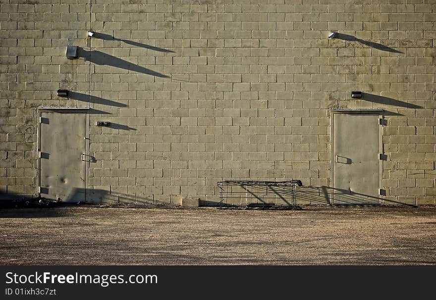 Old cinder block wall with matching dented doors and long shadows