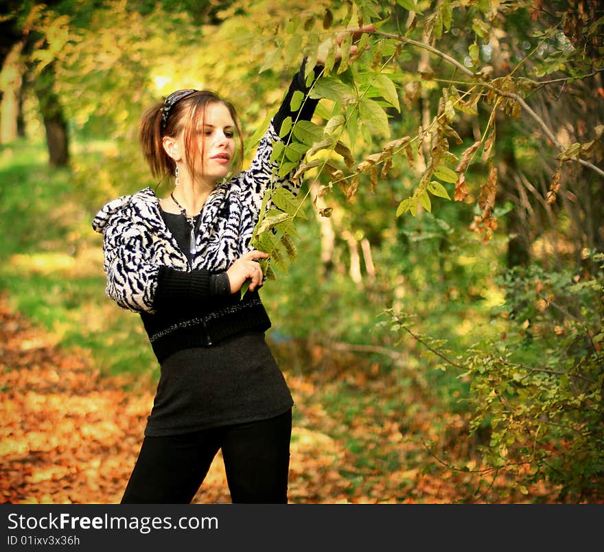 Portrait of the beautiful and happy brunette against red autumn leaves