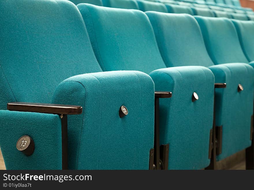 Row number thirteen. Row of green chairs in auditorium. Row number thirteen. Row of green chairs in auditorium.