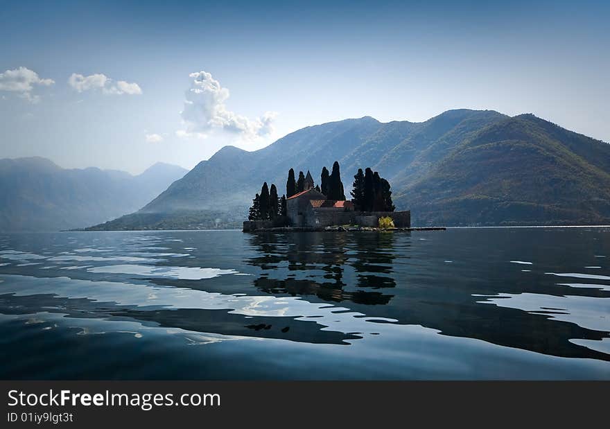 Natural island in Kotor Bay (Montenegro) with a Catholic monastery of St.George. Bright sunny day, mountains in light blue mist on the background