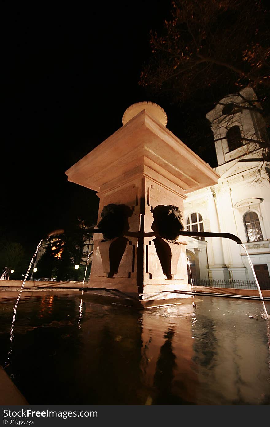 Fountain by night in sremski karlovci city in serbia with church in background