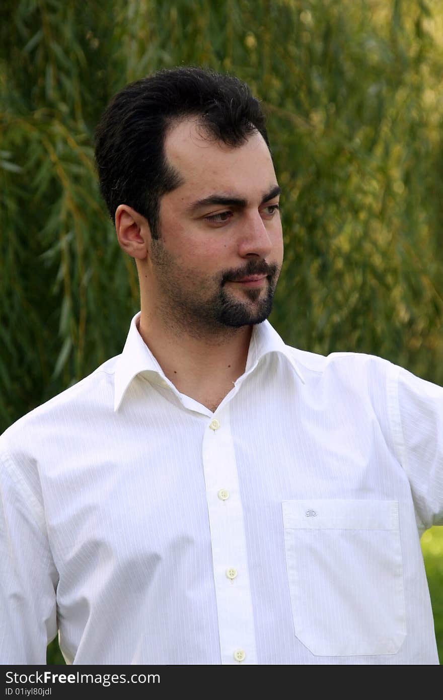 A man in white shirt with the serious look on the green leaves background