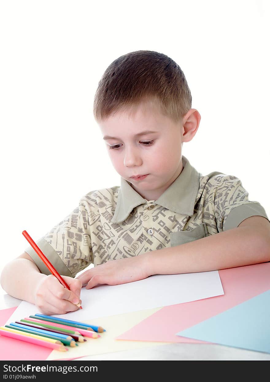 6 year old boy draws pencils sitting for a table. 6 year old boy draws pencils sitting for a table