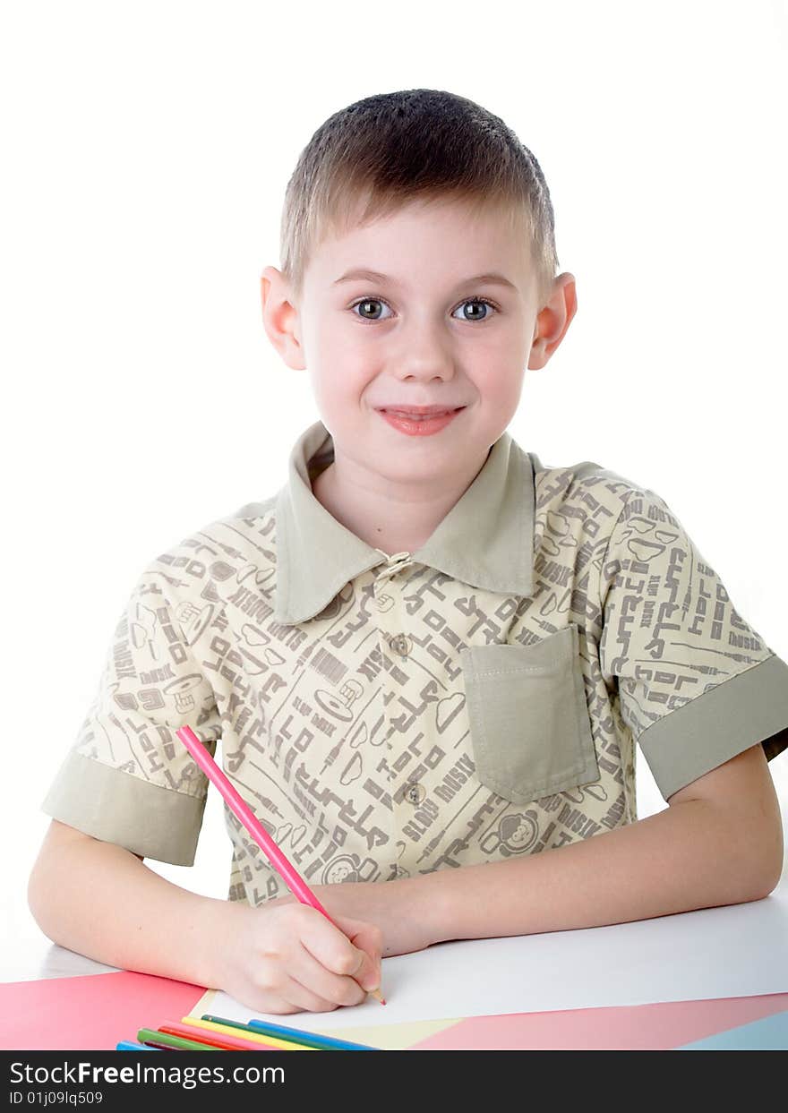 6 year old boy draws pencils sitting for a table. 6 year old boy draws pencils sitting for a table