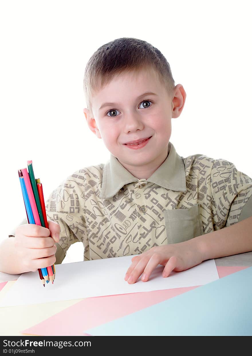 6 year old boy draws pencils sitting for a table. 6 year old boy draws pencils sitting for a table