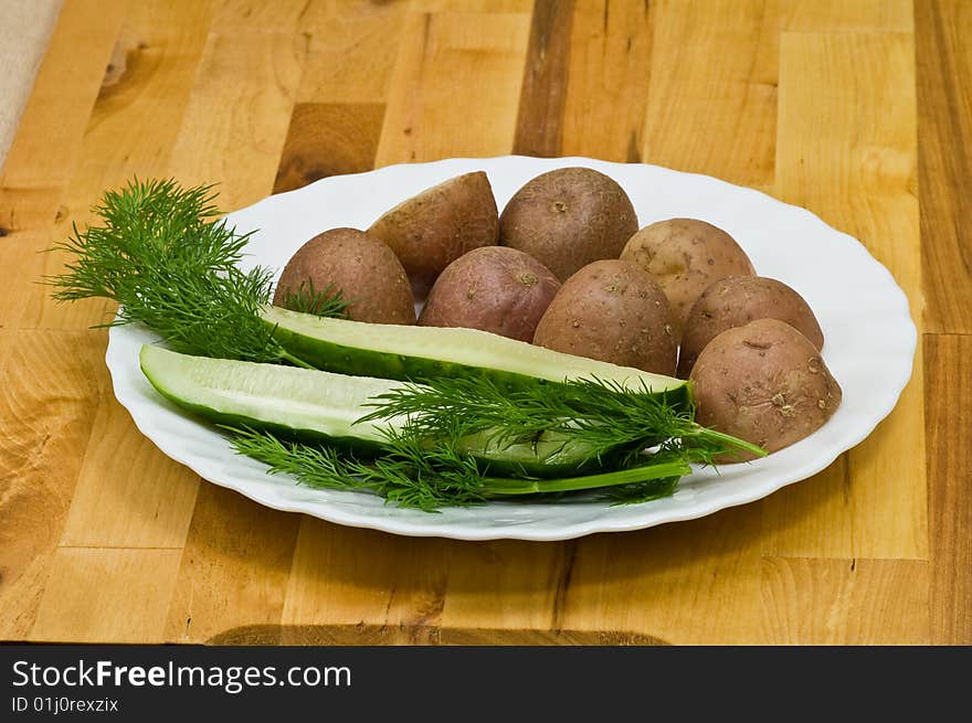 Provincial still-life with boiled potatoes, sliced salt cucumber and some dill on white porcelain  plate. Provincial still-life with boiled potatoes, sliced salt cucumber and some dill on white porcelain  plate