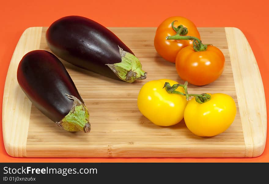 Fresh ripe eggplant and vine ripe tomatoes on a wooden cutting board. Fresh ripe eggplant and vine ripe tomatoes on a wooden cutting board