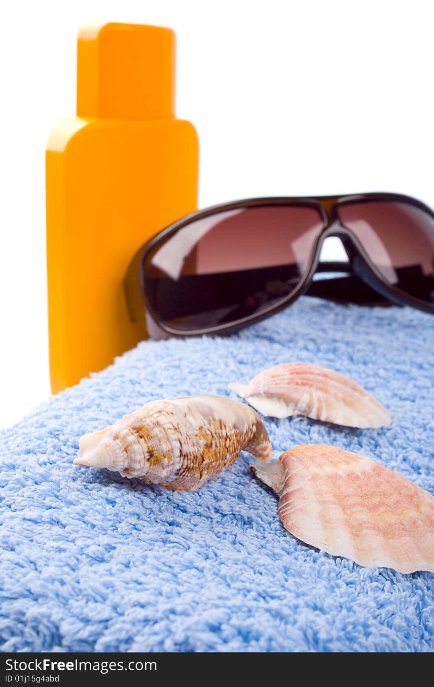 Towel, shells, sunglasses and lotion closeup on white background