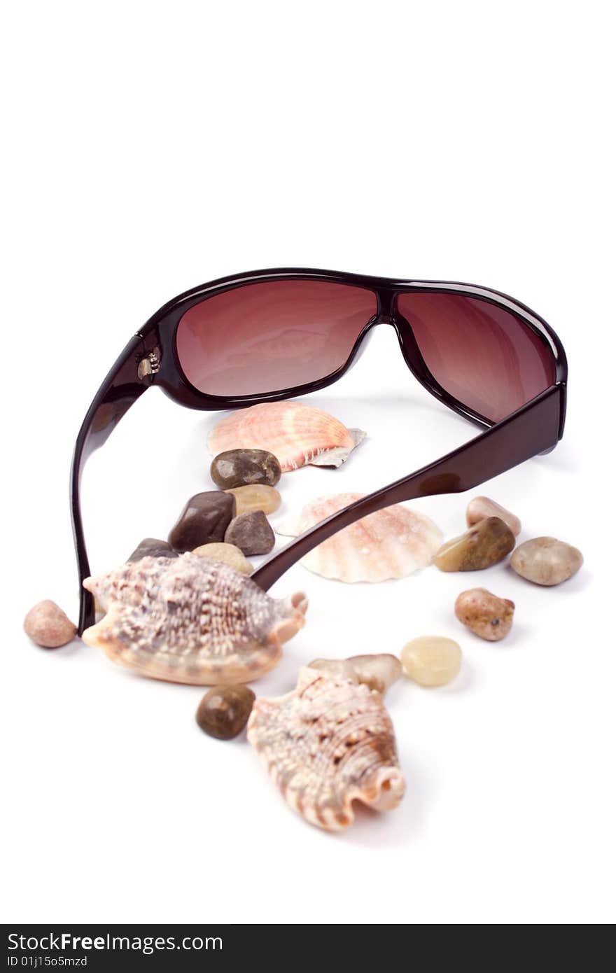 Sunglasses, shells and pebbles closeup on white background