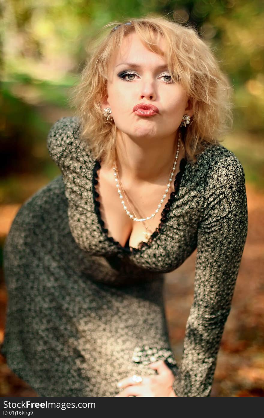 Portrait of the beautiful and happy blonde against red autumn leaves