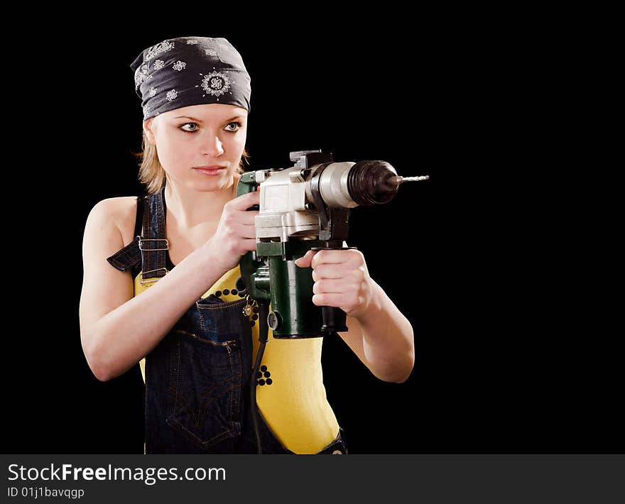 Severe young woman with a drill on black background