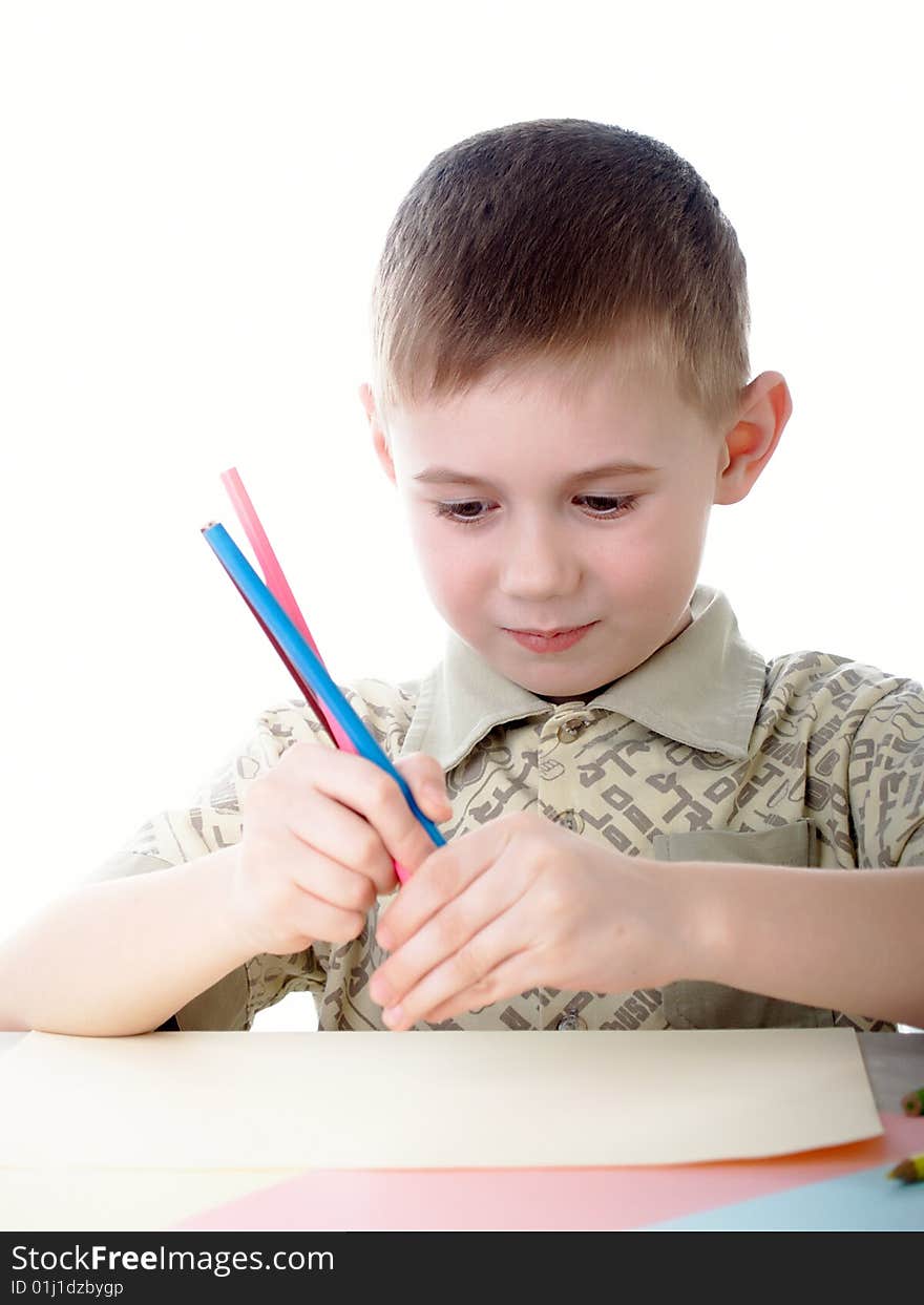 6 year old boy draws pencils sitting for a table. 6 year old boy draws pencils sitting for a table