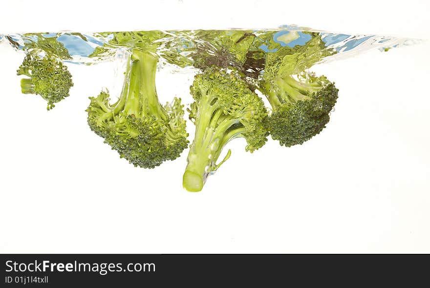 Broccoli is falling into water. Broccoli is falling into water