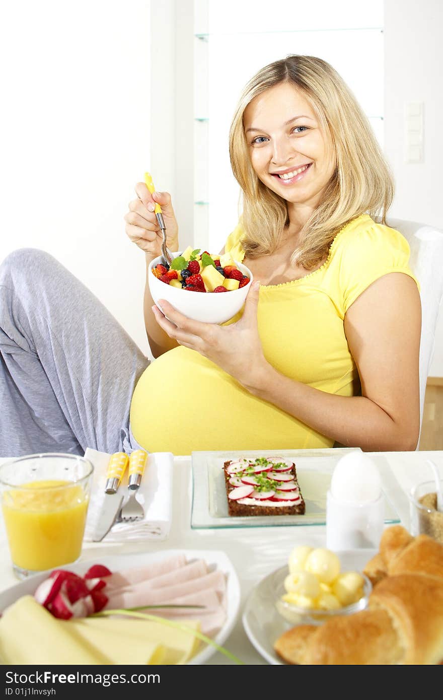 Young pretty pregnant woman sits at the breakfast table. Young pretty pregnant woman sits at the breakfast table